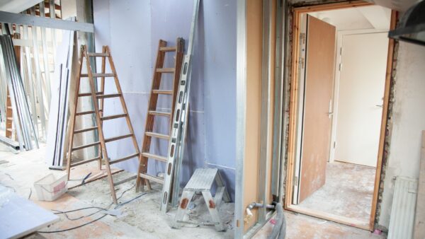 Inside a house under construction with ladders, drywall and dust.
