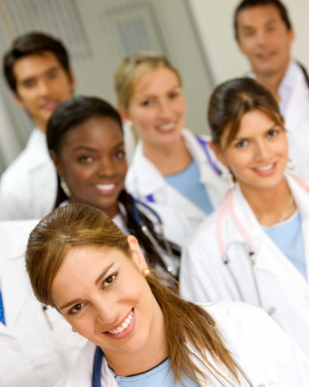 Women and men of different ages and backgrounds in a group - medical professionals wearing white lab coats and stethoscopes